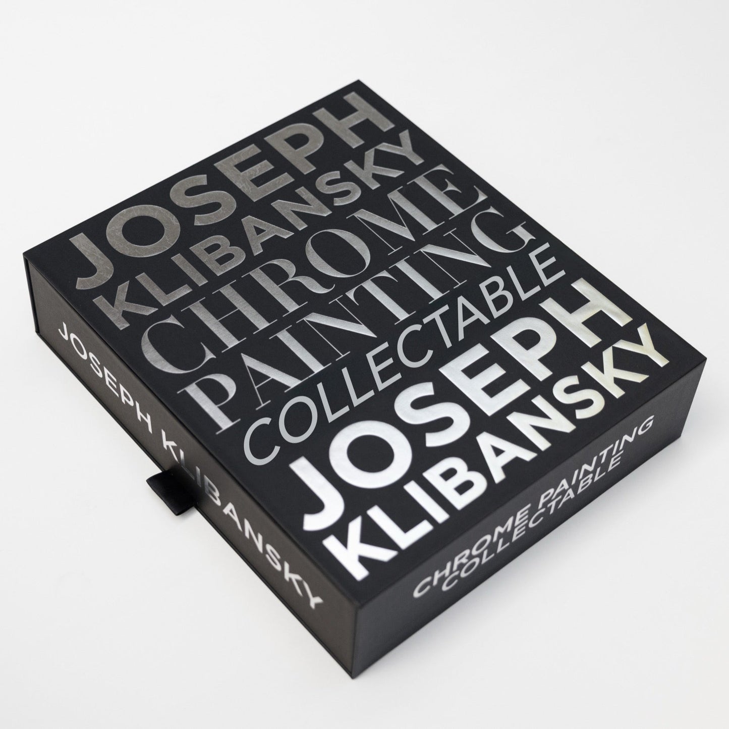 A black box with chrome foil silver text on it, by Joseph Klibansky chrome painting collectible in its closed position on a white background.