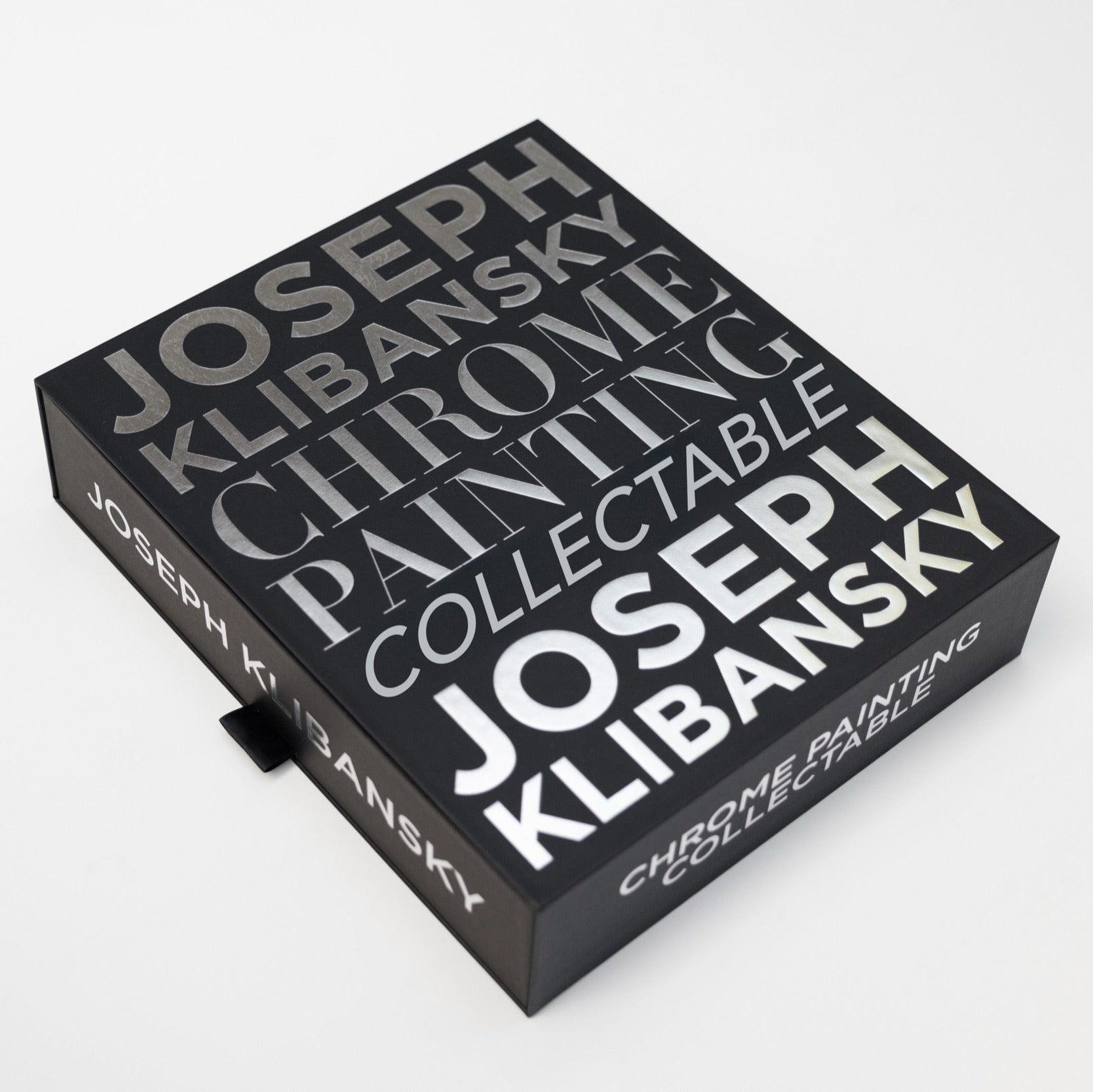 A black box with chrome foil silver text on it, by Joseph Klibansky chrome painting collectible in its closed position on a white background.